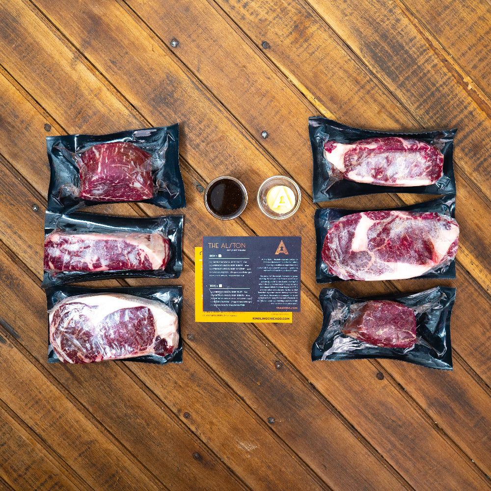 Raw steaks in packaging on a wooden surface with a card and small containers.