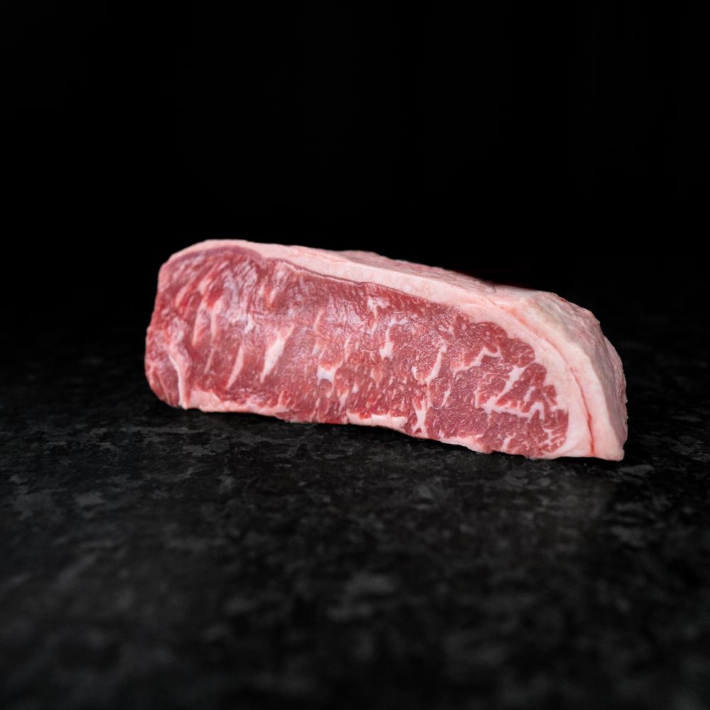 American Wagyu New York Strip Steak with bold marbling and rich flavor, ideal for grilling